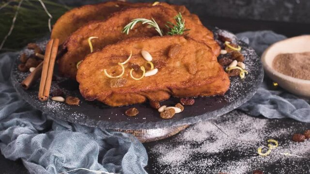 Traditional Christmas Rabanadas with lemon zest, raisins, pine nuts and cinnamon. Spanish Torrijas or french toasts close up on the countertop