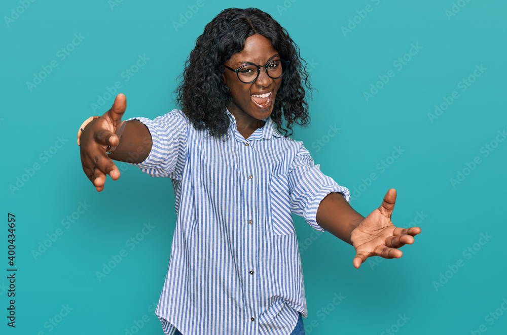 Wall mural beautiful african young woman wearing casual clothes and glasses looking at the camera smiling with 