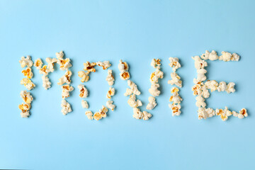 Word MOVIE made of tasty popcorn on color background