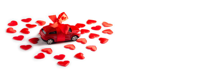 Red toy car with ribbon stands in hearts on a white background, banner, copy space, horizontal orientation