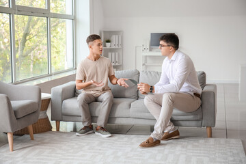 Psychologist working with teenage boy in office