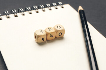 Abbreviation SEO with notebook and pencil on dark background, closeup