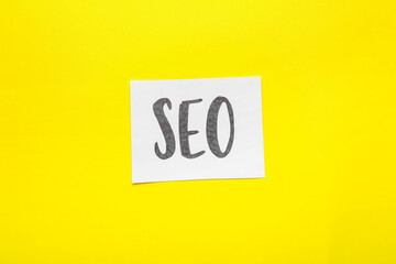 Paper sheet with abbreviation SEO on color background