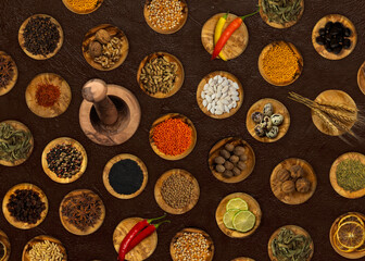 Top view of spices and food ingredients in wooden small plates and a wooden Mortar .