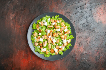 top view caesar salad on oval plate on dark red background free space