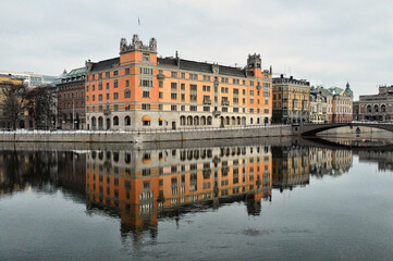Fototapeta na wymiar An orange historical building in Stockholm is fully reflected in the river