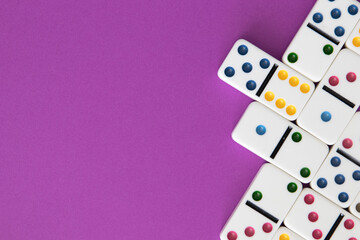 Colorful dominoes arranged on purple background with negative space for copy