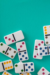Colorful dominoes arranged on aqua blue background with negative space for copy