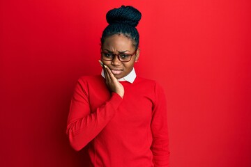 Young african american woman wearing casual clothes and glasses touching mouth with hand with painful expression because of toothache or dental illness on teeth. dentist