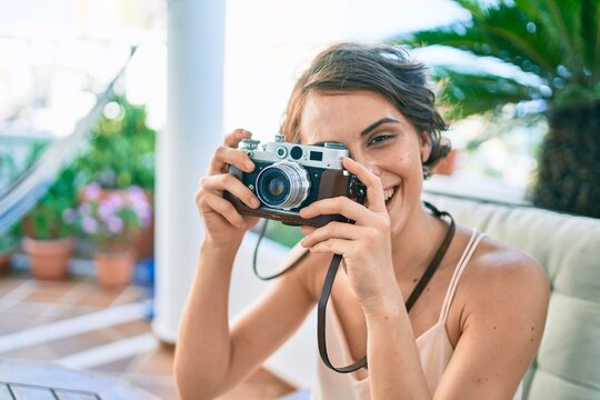 Young beautiful caucasian woman smiling happy at home taking pictures using vintage camera