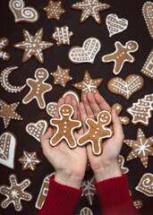 Child's hands holding homemade two Gingerbread man cookies. Christmas sweet food concept. Flat lay. Rustic style.