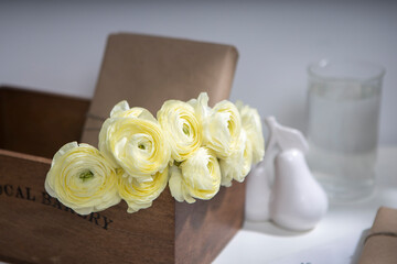Bouquet of yellow ranunculus in a wooden box with wrapped gifts