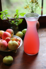 Tasty organic homemade pink juice from apples and garden berries on rustic wooden table of country house. Eco food in summer. 