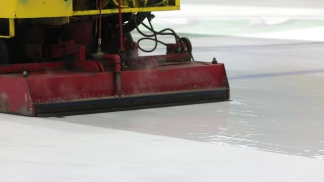 Resurfacing machine cleaning ice of hockey rink. Special machine for cleaning ice on an ice rink at work. Ice harvesters