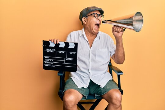 Handsome Mature Director Man Holding Video Film Clapboard And Louder Angry And Mad Screaming Frustrated And Furious, Shouting With Anger. Rage And Aggressive Concept.