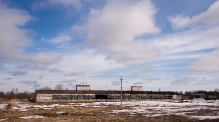 Fototapeta na wymiar Winter landscape with old abandoned cowshed and field covered with snow