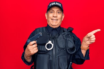 Senior man with grey hair wearing police uniform holding gun smiling happy pointing with hand and finger to the side