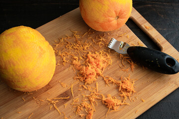 Zesting Navel Oranges: Two oranges and a zester on a bamboo cutting board - Powered by Adobe
