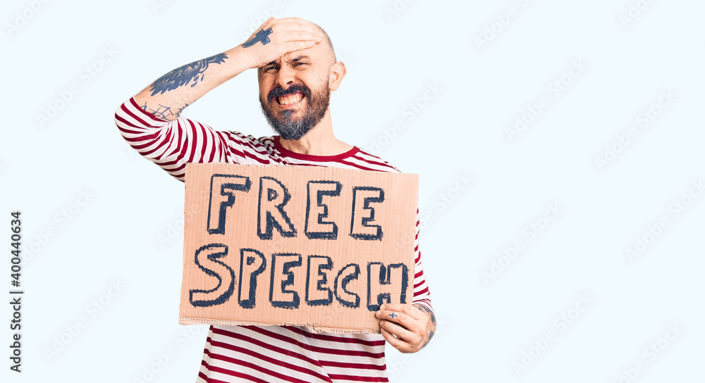 Poster young handsome man holding free speech banner stressed and frustrated with hand on head, surprised a