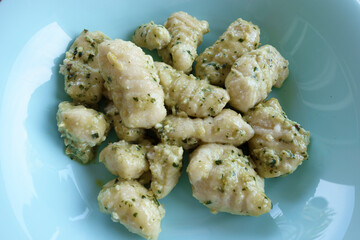 Gnocchi with pesto on a blue plate