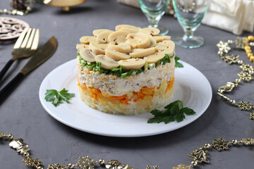 Puff salad with chicken, pickled mushrooms, potatoes and carrots on plates. New Year's composition.