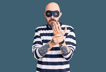 Young handsome man wearing burglar mask suffering pain on hands and fingers, arthritis inflammation