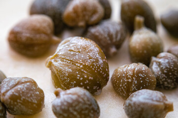 macro close-up of pickled green capers on white base