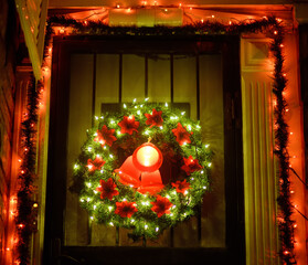 Christmas green wreath with red bells on the front door. Entrance to the house decorated for the winter holiday - Xmas and New Year.