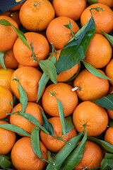 Flat lay view of a container of clementines on the stall of an italian food market. Full frame close up of the nuts for wallpaper use. Bright saturated colors.