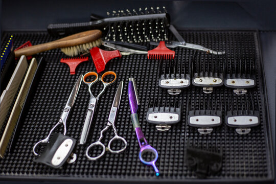 Master's table with tools in a hairdressing salon, top view. Set of tools for sewing scissors, straight razors, clipper heads, combs, hairpins