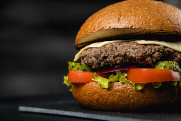 Huge delicious Burger on a dark background. Meat and vegetables.