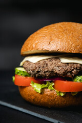 Huge delicious Burger on a dark background. Meat and vegetables.