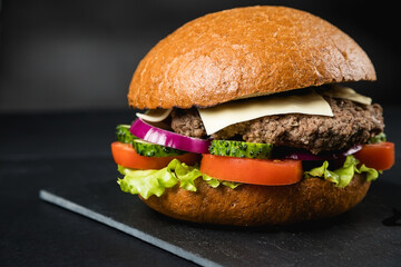 Huge delicious Burger on a dark background. Meat and vegetables.