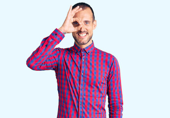 Fototapeta premium Young handsome man wearing casual clothes doing ok gesture with hand smiling, eye looking through fingers with happy face.