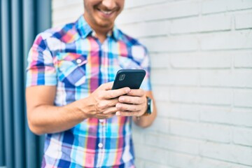 Young caucasian man smiling happy using smartphone at the city.