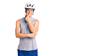 Young handsome man wearing bike helmet looking confident at the camera smiling with crossed arms and hand raised on chin. thinking positive.