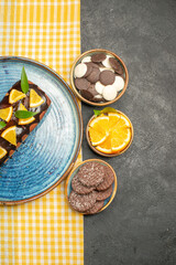 Vertical view of delicious cake on yellow stripped towel and biscuits on black table