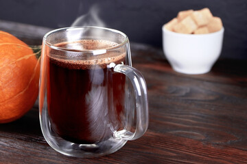 A cup of black coffee on wooden table. A glass mug of coffee. Pumpkin and cane sugar on a wooden background. Morning coffee