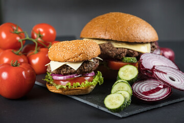 Huge delicious Burger on a dark background. Meat and vegetables.