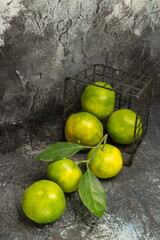 Vertical view of fallen basket with fresh green tangerines on gray background stock image