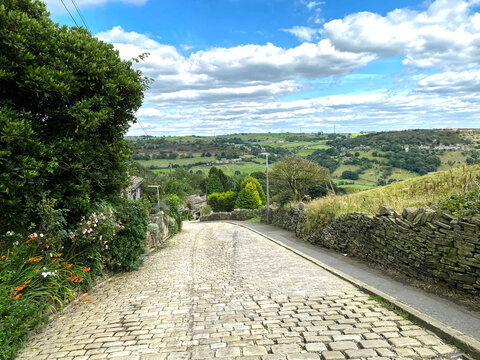Looking down, Lee Lane, with flowers, dry stone walls, and a cobbled road in, Halifax, Yorkshire, UK