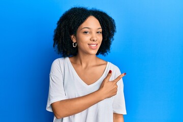 Young african american girl wearing casual white t shirt smiling cheerful pointing with hand and finger up to the side