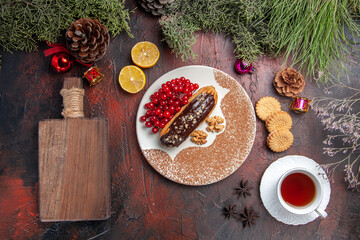 top view yummy choco eclairs with tea and berries on the dark background sweet cake pie dessert