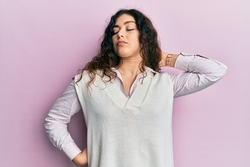 Young brunette woman with curly hair wearing casual clothes suffering of neck ache injury, touching neck with hand, muscular pain