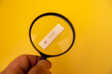 Rapid antigen test seen from a magnifying glass.