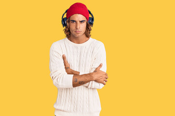 Young hispanic man listening to music using headphones skeptic and nervous, disapproving expression...