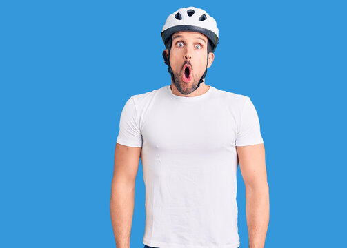 Young handsome man wearing bike helmet afraid and shocked with surprise expression, fear and excited face.