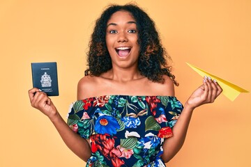 Young african american woman holding paper airplane and canadian passport celebrating crazy and amazed for success with open eyes screaming excited.