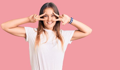 Beautiful caucasian woman wearing casual white tshirt doing peace symbol with fingers over face, smiling cheerful showing victory