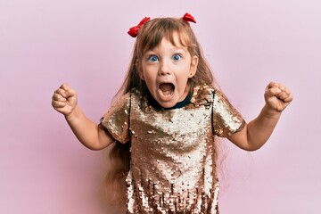 Little caucasian girl kid wearing festive sequins dress celebrating surprised and amazed for...